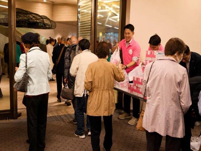 体験会で商品を手渡すスタッフと参加者の様子